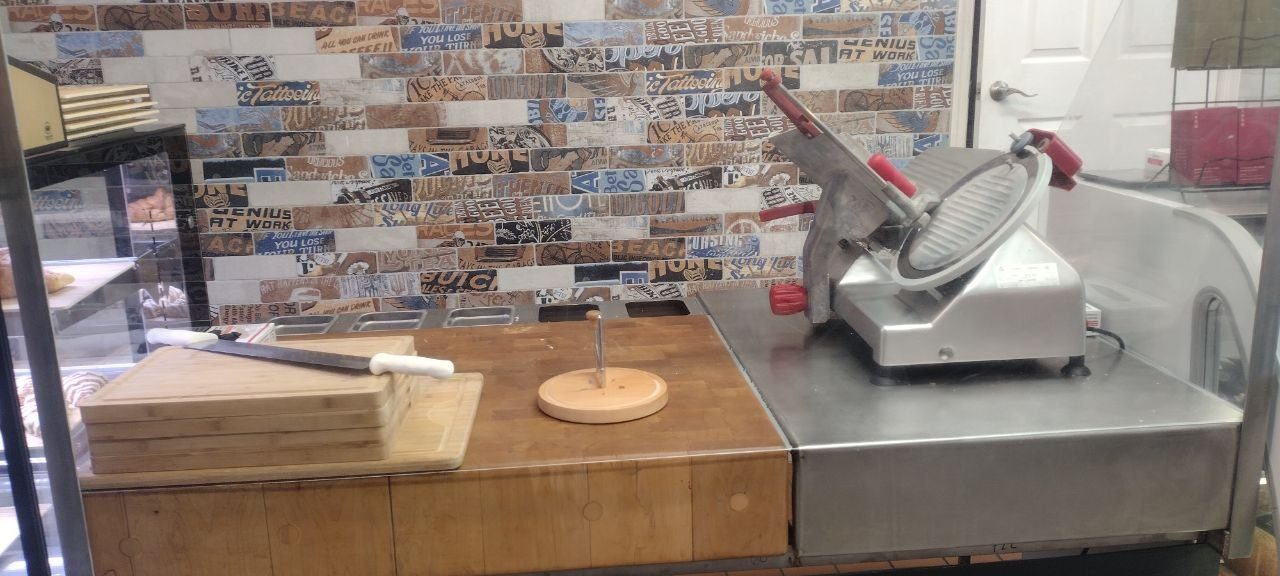 Commercial deli slicer with cured meats and cigar-band tile backsplash