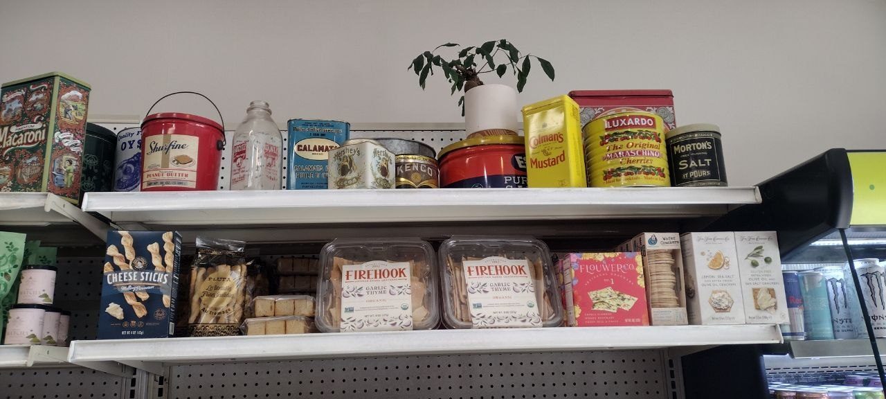 Vintage tin display — Macaroni, Oysters, Shurfine peanut butter, Hershey's, Kenco, Colman's Mustard, Luxardo cherries, Morton's salt — above Firehook crackers and Flouwer Co. olive-oil crackers